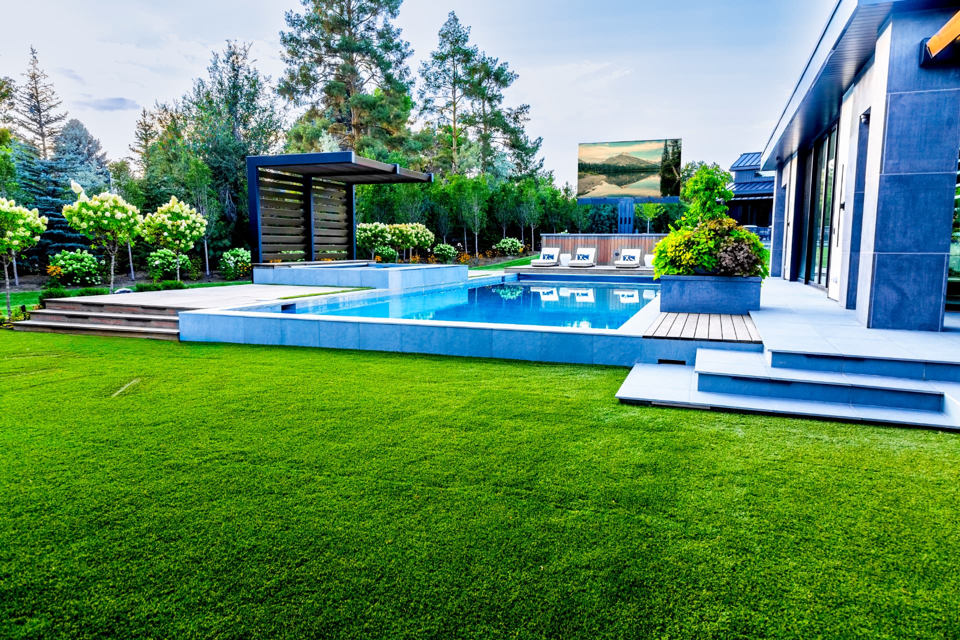 Backyard pool with a large weather-rated outdoor television and landscape lighting