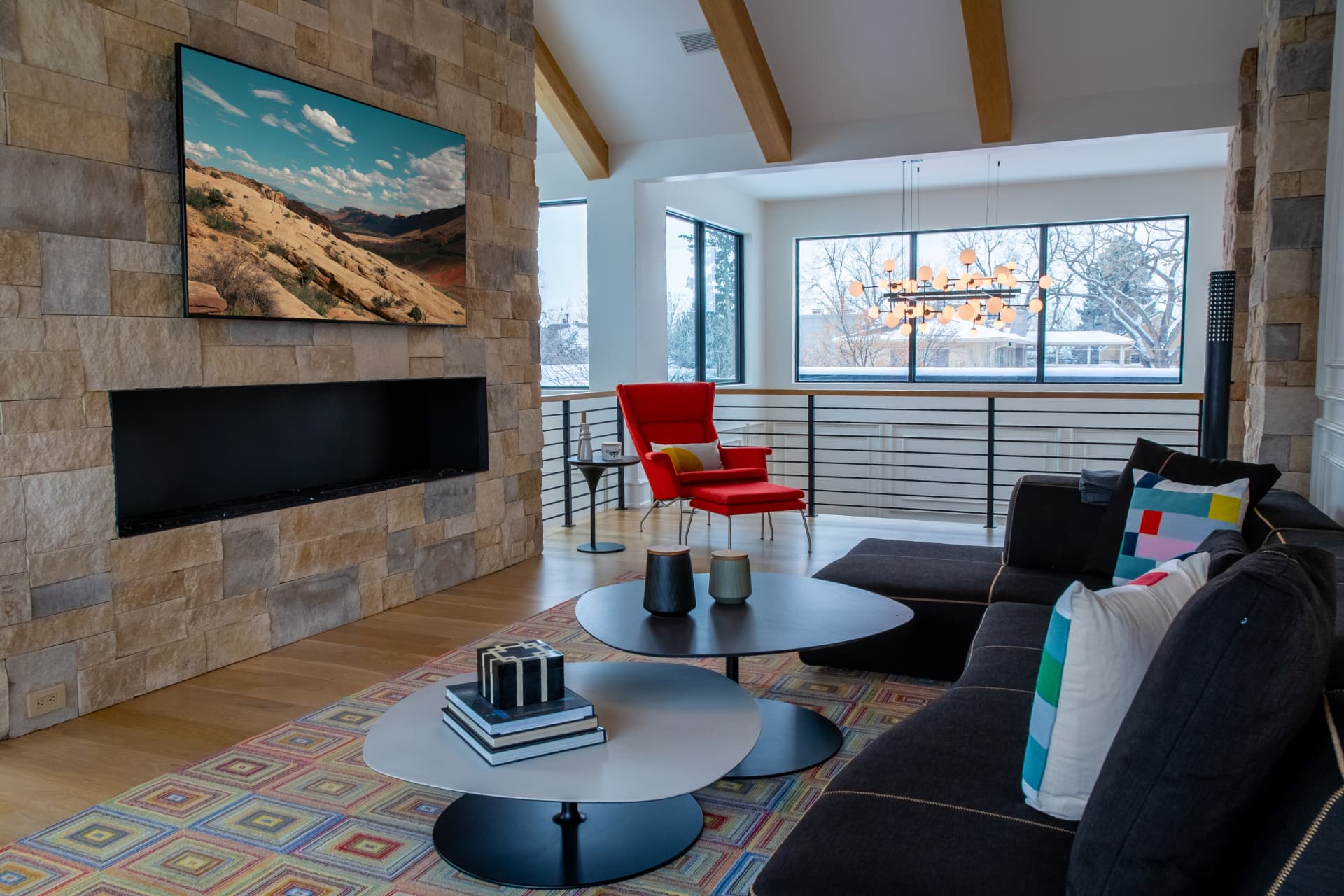 Media loft with a television mounted on a stone fireplace wall and vaulted beamed ceiling