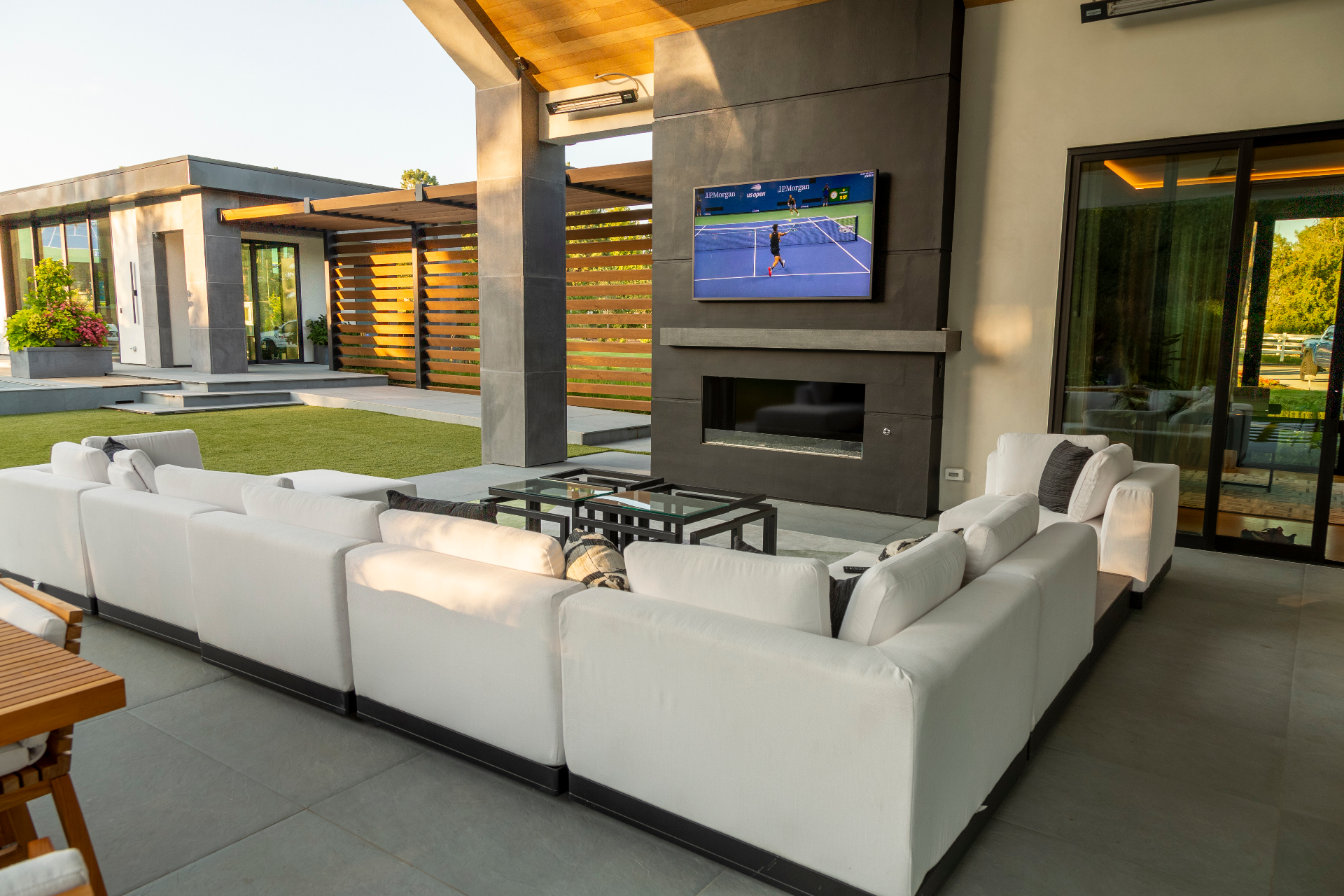 Covered outdoor lounge with weatherproof TV, fireplace, and modern seating